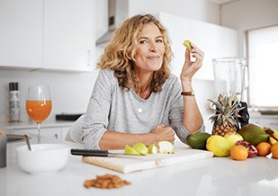 Woman smiling while eating snack in kitchen