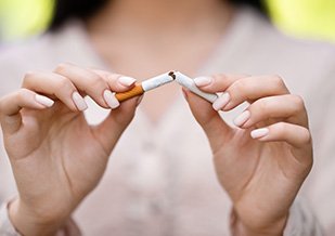 Closeup of woman breaking cigarette