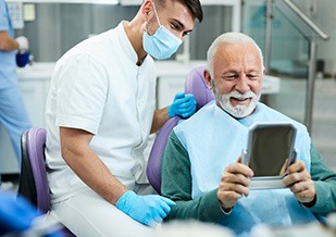 Senior man smiling at reflection in handheld mirror