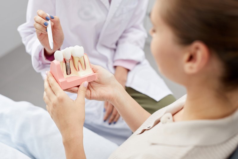 A dental patient holding an enlarged dental implant model